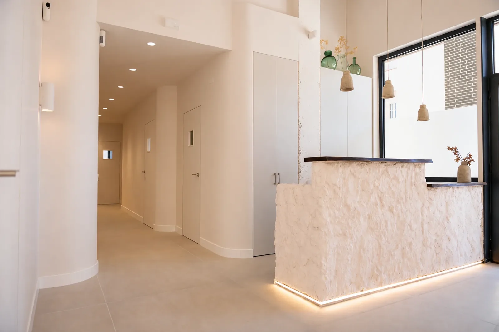 Recepció de la clínica dental MÜN a Montgat amb mostrador de textura pètria i llum rasant